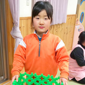 オレンジのジャージを着ておもちゃを抱える小倉美咲（小学三年生）。