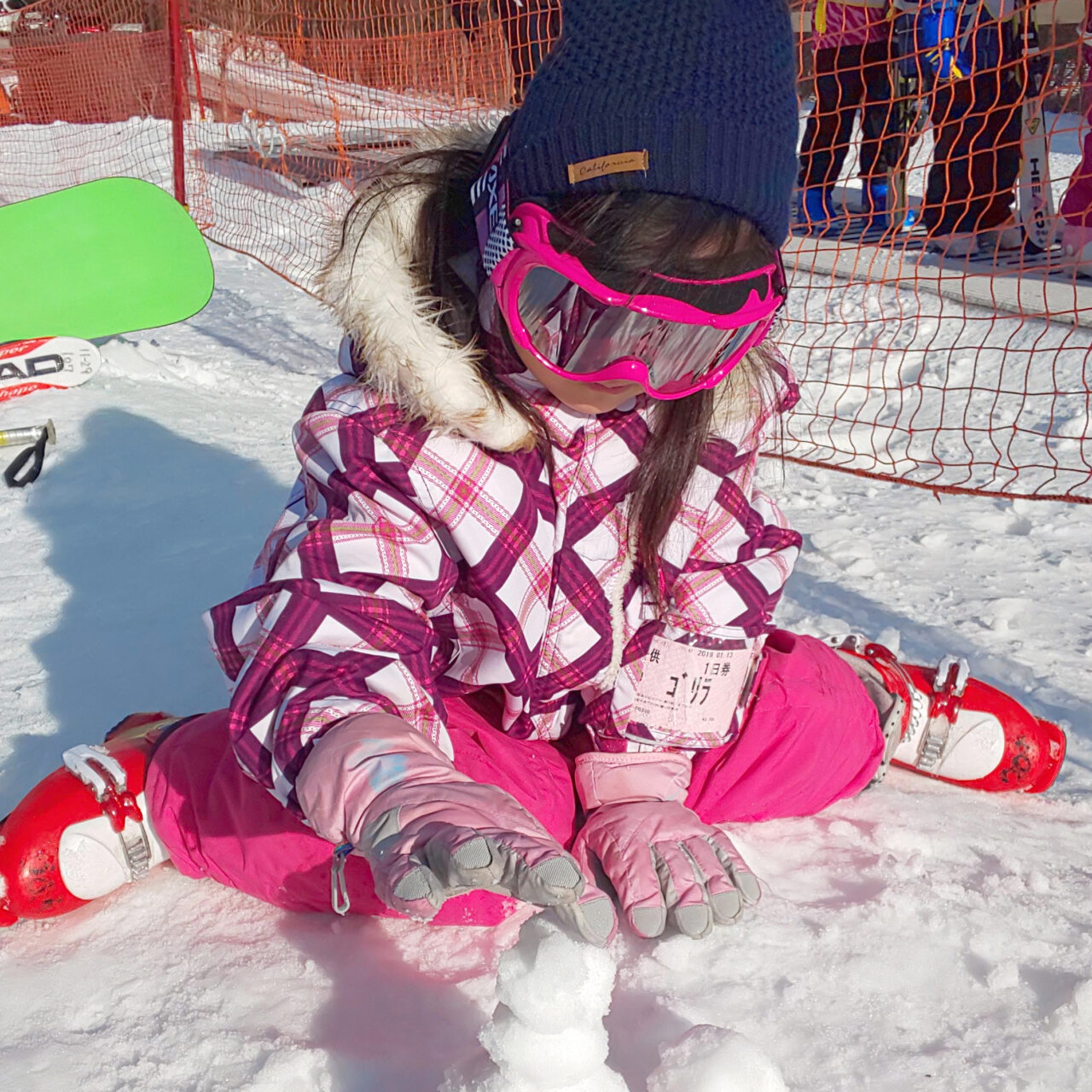 ピンク色の防寒着とゴーグルをして雪景色の中、雪遊びする小倉美咲（おぐらみさき）。