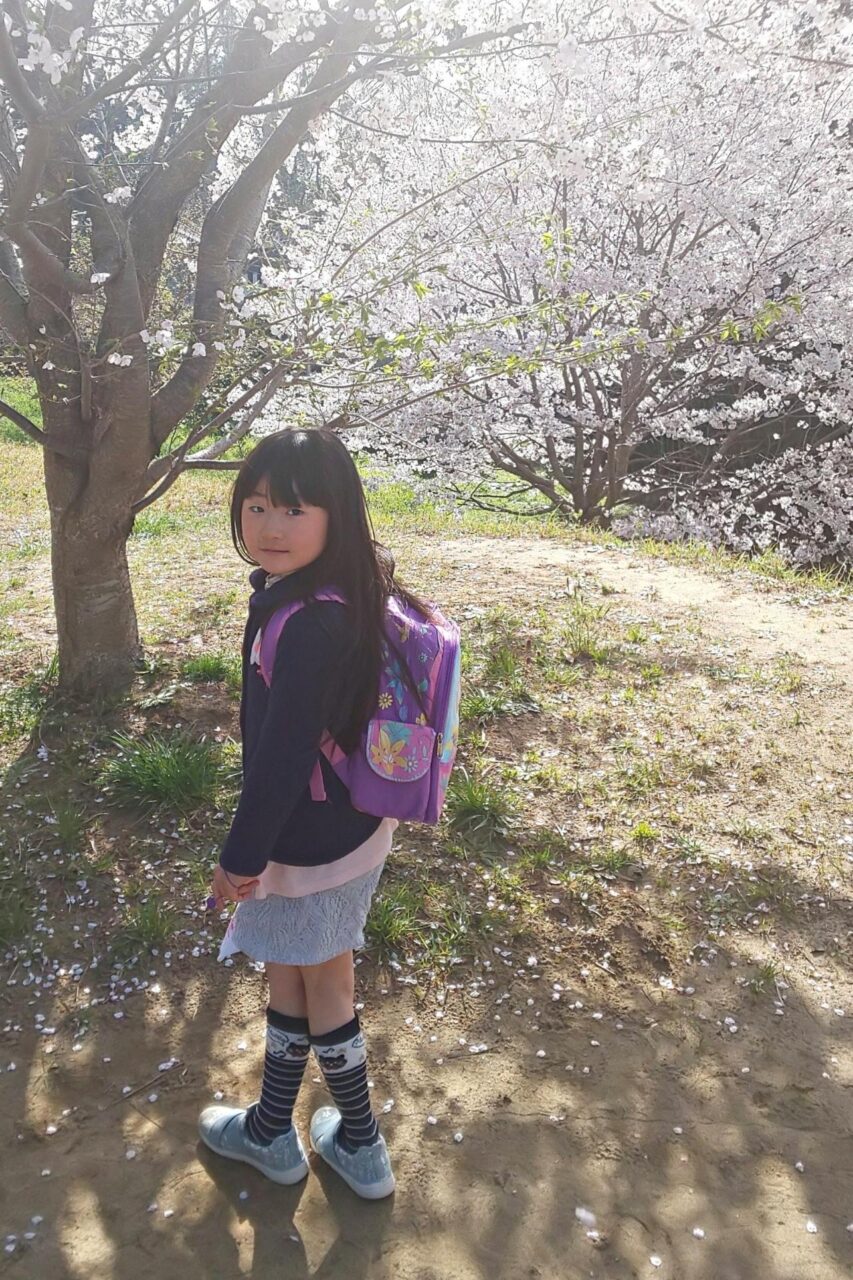 桜の木と一緒に写る小倉美咲